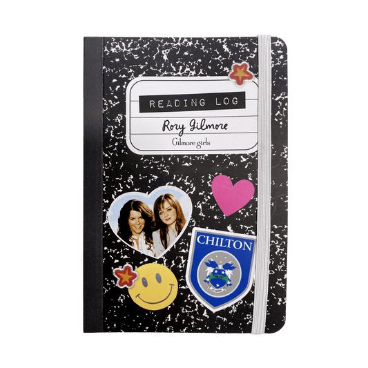 A personalized black and white speckled composition notebook with an elastic closure band, featuring custom stickers including a heart-shaped photo, a pink heart, and a blue Chilton crest, with a 'Reading Log' label at the top.