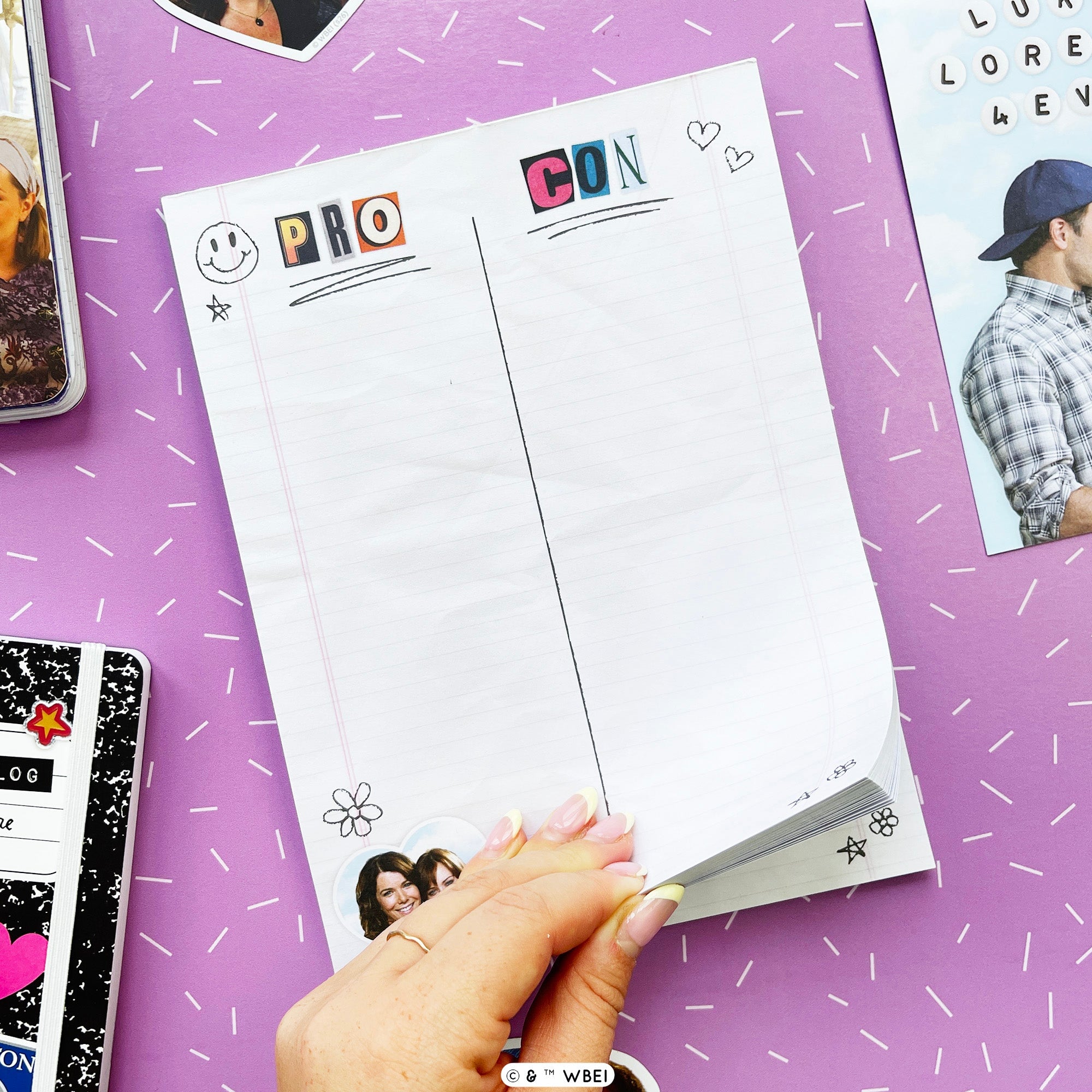 A hand holds a stack of white lined notepad sheets with colorful decorative headers reading 'PRO' and 'CON' on a purple background with scattered doodles and stationery props.